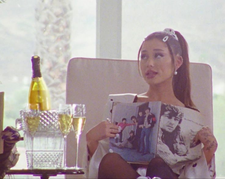 a woman sitting in a chair holding up a magazine