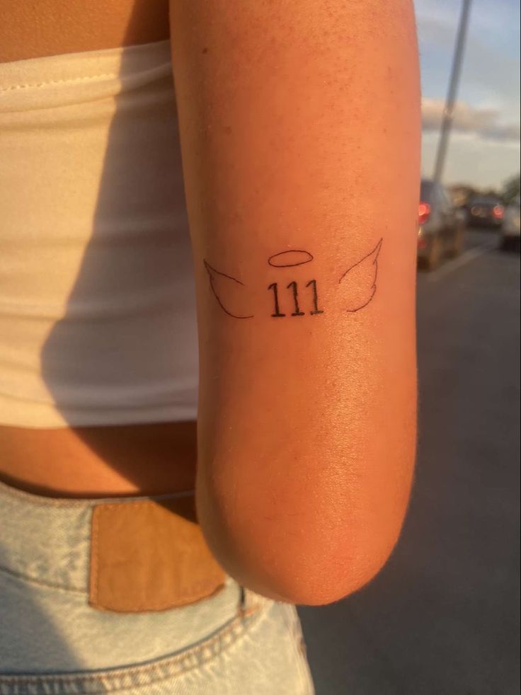 a woman's arm with a small tattoo on it that reads 11 / 11