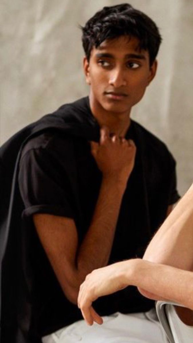 a man and woman sitting next to each other in front of a white wall wearing black clothing