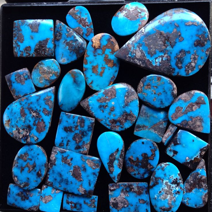 several pieces of turquoise colored rocks in a black box with rusted paint on them