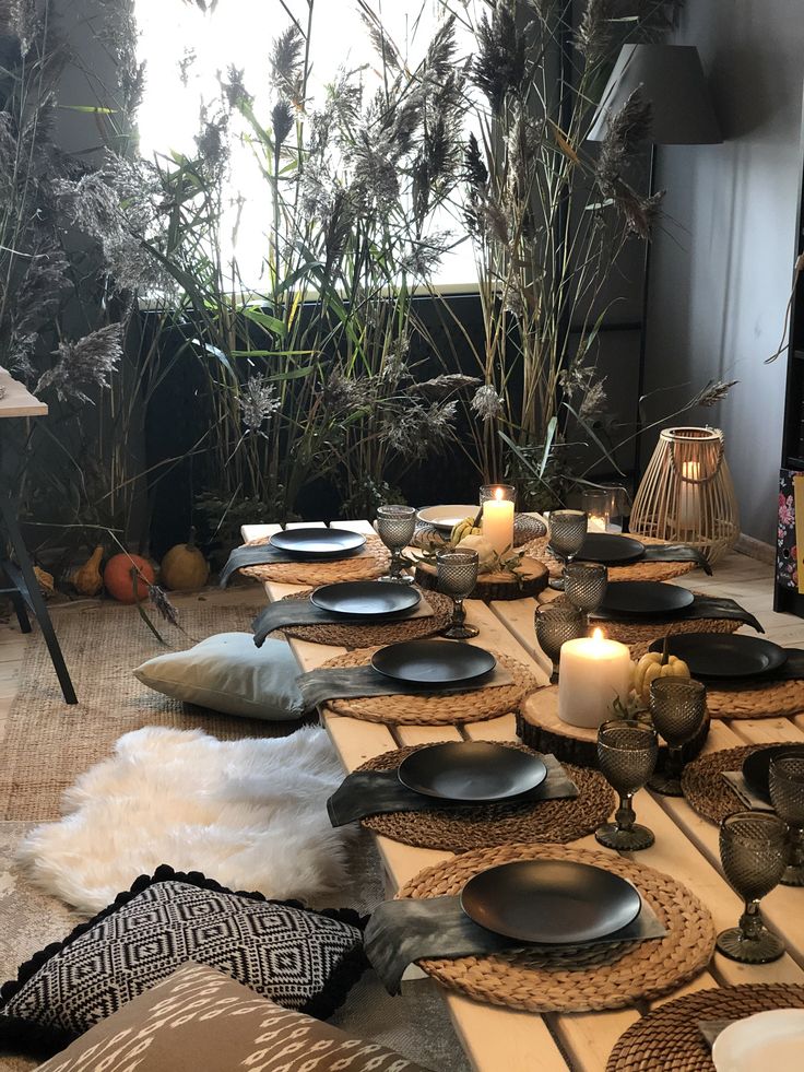 the table is set with black plates and candles