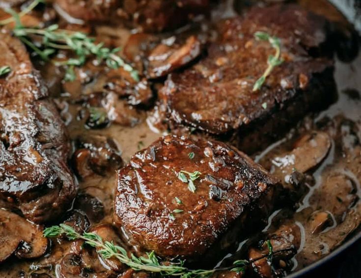 some meat and mushrooms are cooking in a skillet