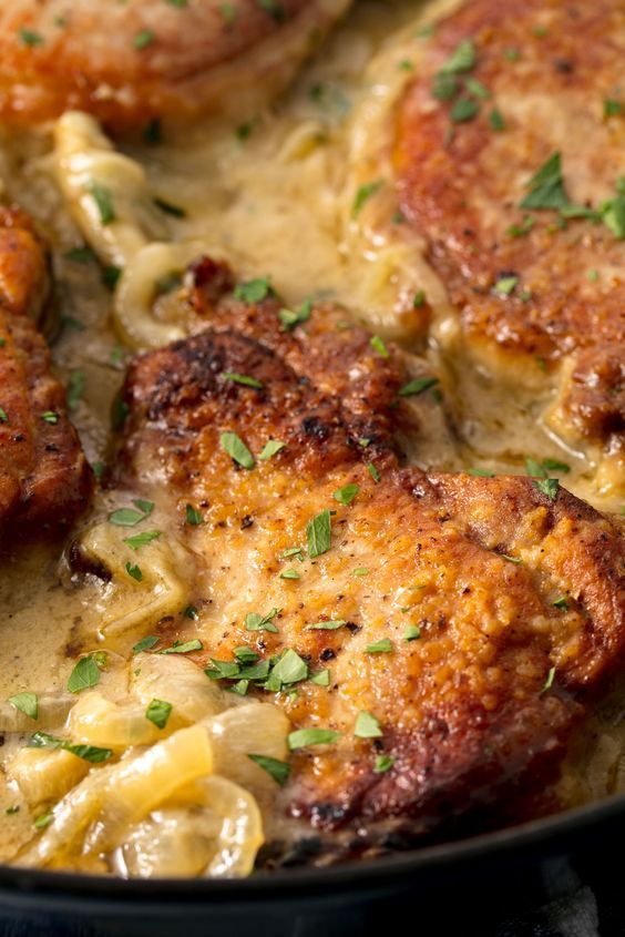 some meat and noodles are cooking in a skillet with gravy on the side