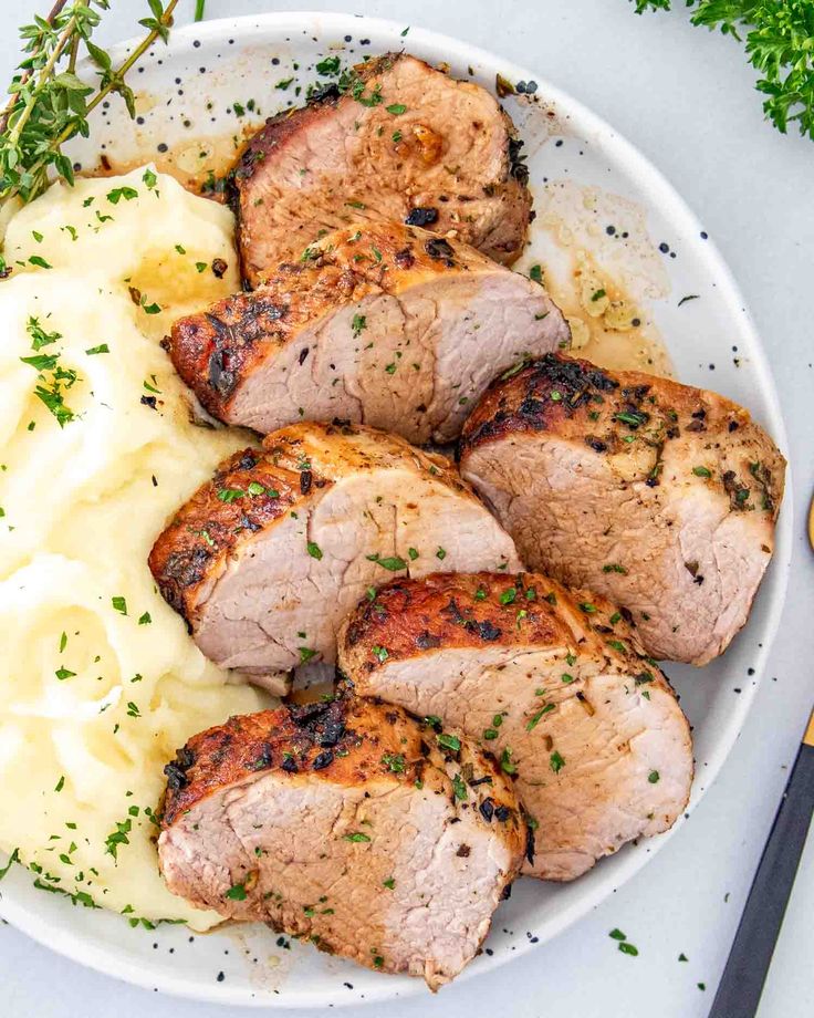 pork chops and mashed potatoes on a white plate with parsley garnish