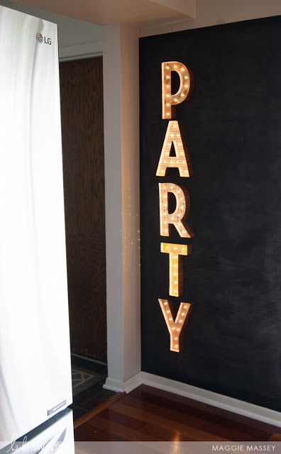 a party sign is lit up in front of a black wall with the word party on it