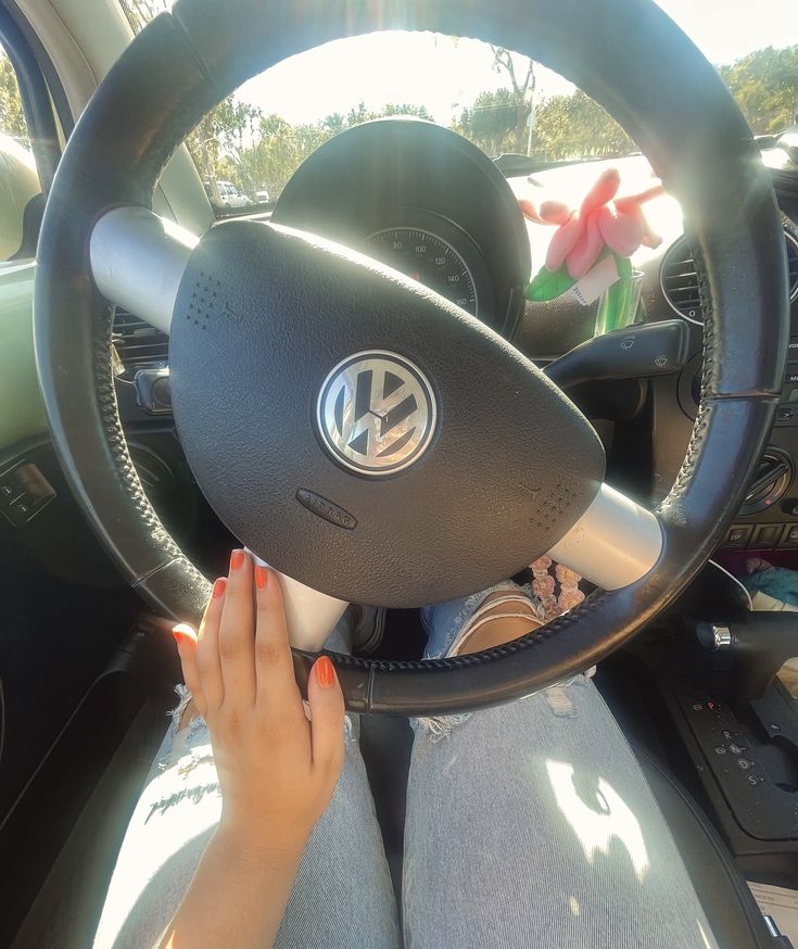 a woman is sitting in the driver's seat of a car with her hands on the steering wheel