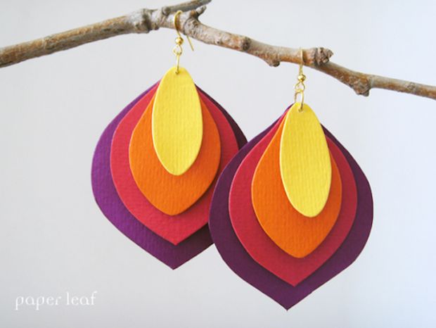 two pairs of colorful earrings hanging from a tree branch on a sunny day with the sky in the background