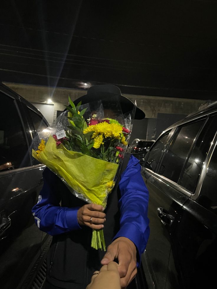 a person holding flowers in front of a car