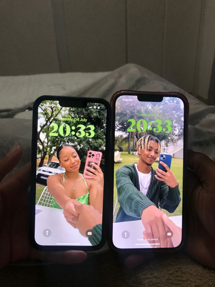 two people holding up their cell phones with the same image on them, and one person taking a selfie