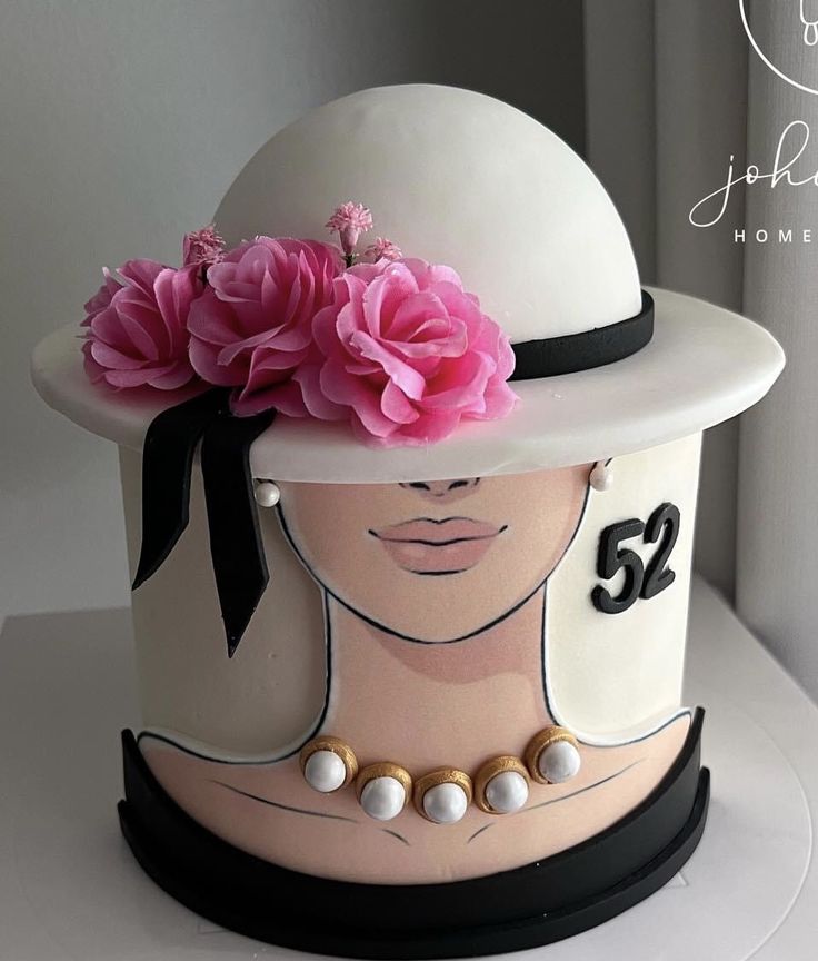 a white hat with pink flowers on top and number 52 on the side, sitting on a table in front of a window