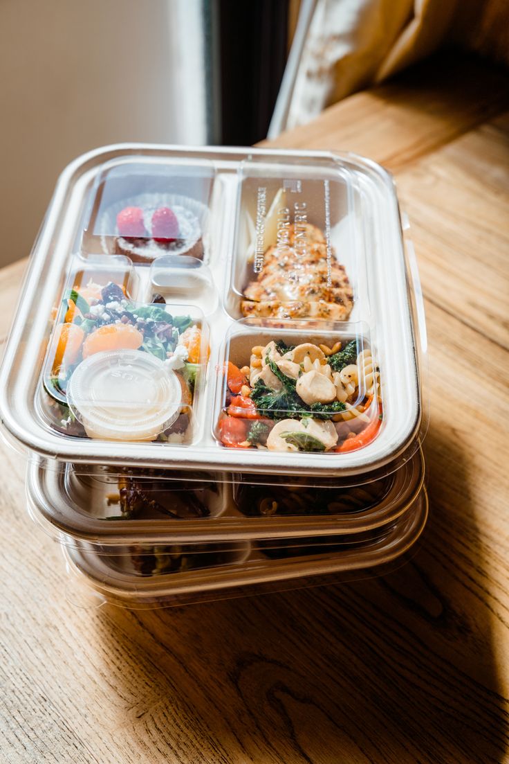 a plastic container filled with food on top of a wooden table