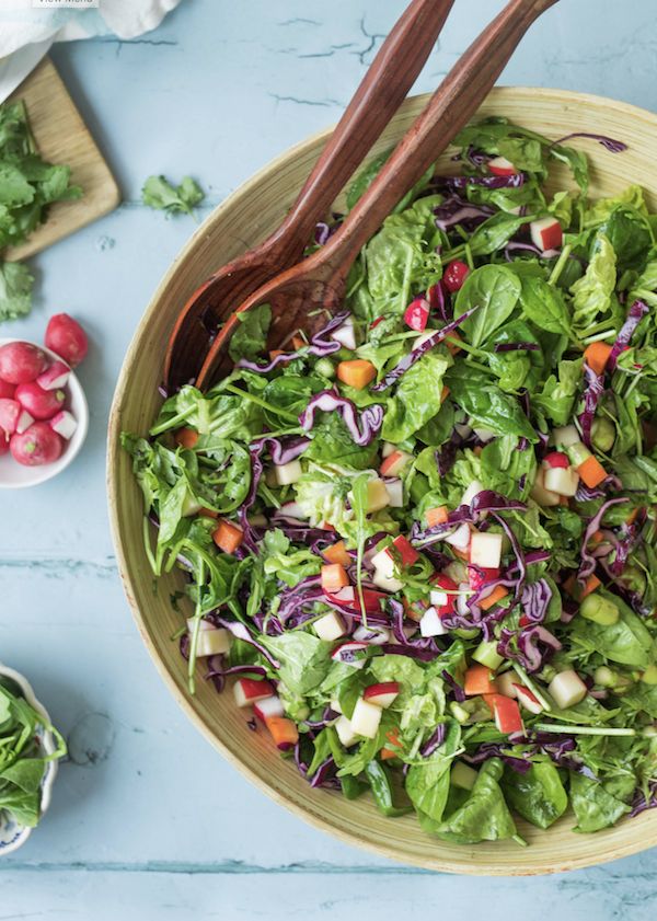 a salad with lettuce, carrots and radishes in a wooden bowl