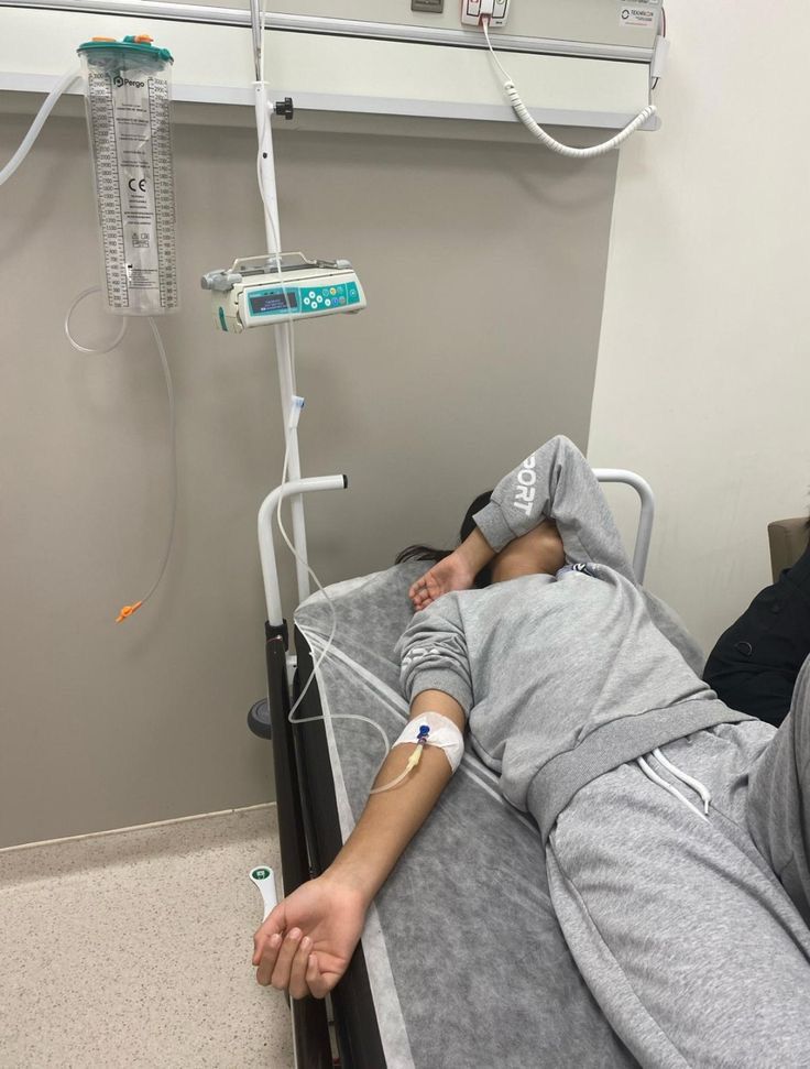 a person laying in a hospital bed with an iv hooked up to the wall behind them