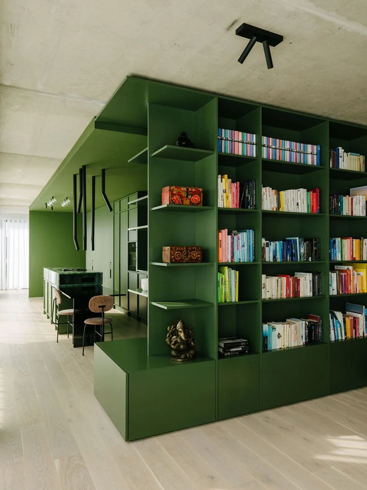 a room filled with lots of green bookshelves