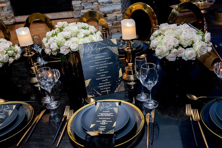 a table set with black and gold place settings