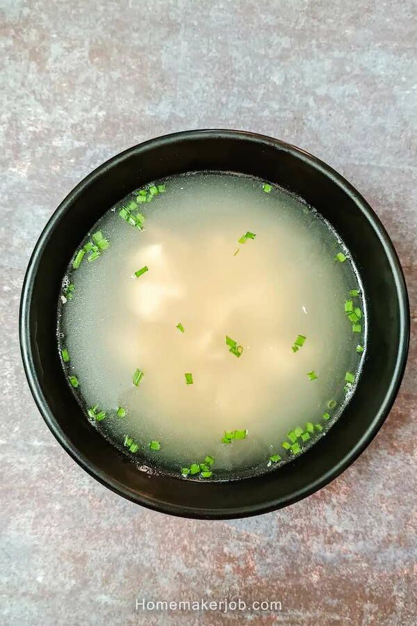 a black bowl filled with soup on top of a table