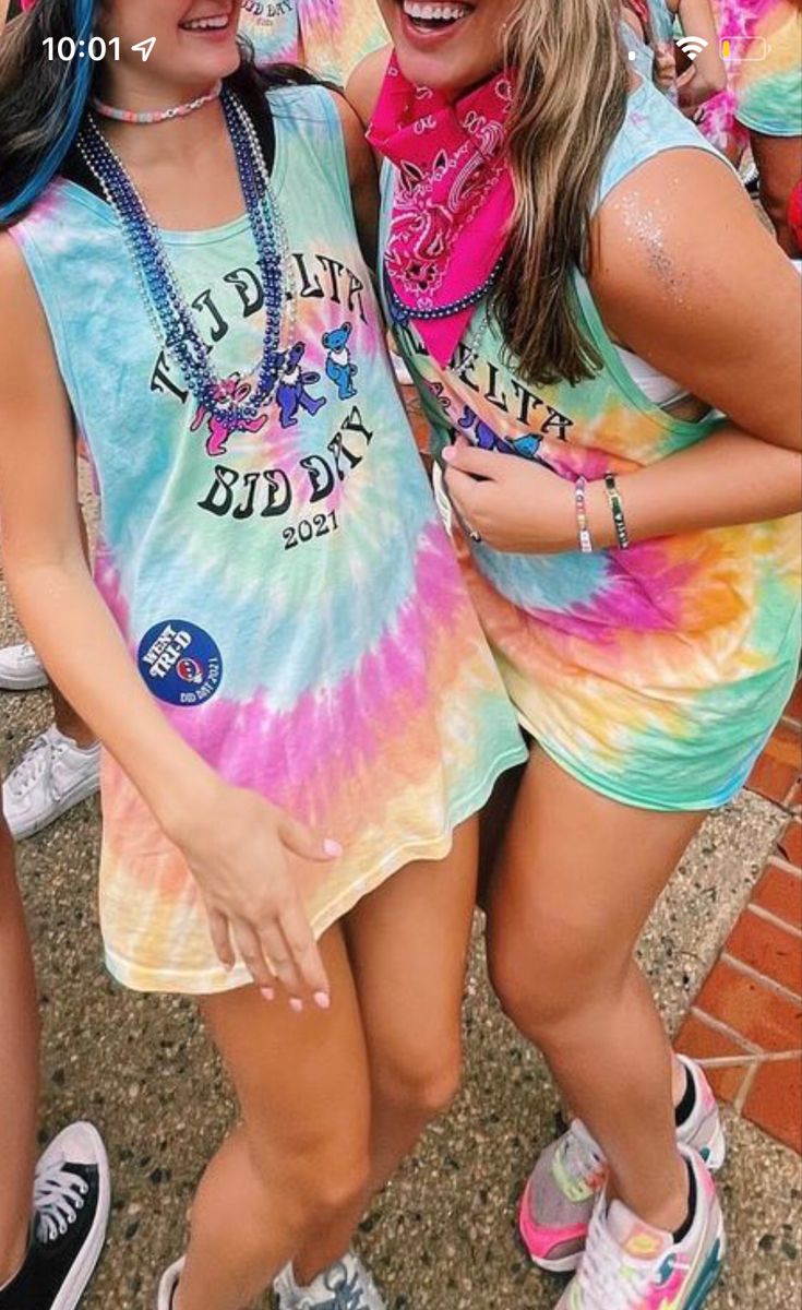 two girls are posing for the camera with their arms around each other while wearing colorful clothing