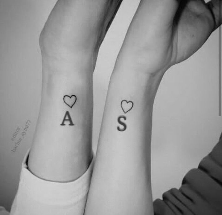 two people with matching tattoos on their arms, one has the letter s and the other has