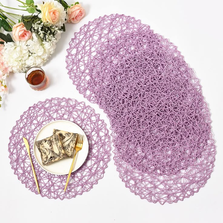 purple crocheted placemats and plates with flowers on the table next to them