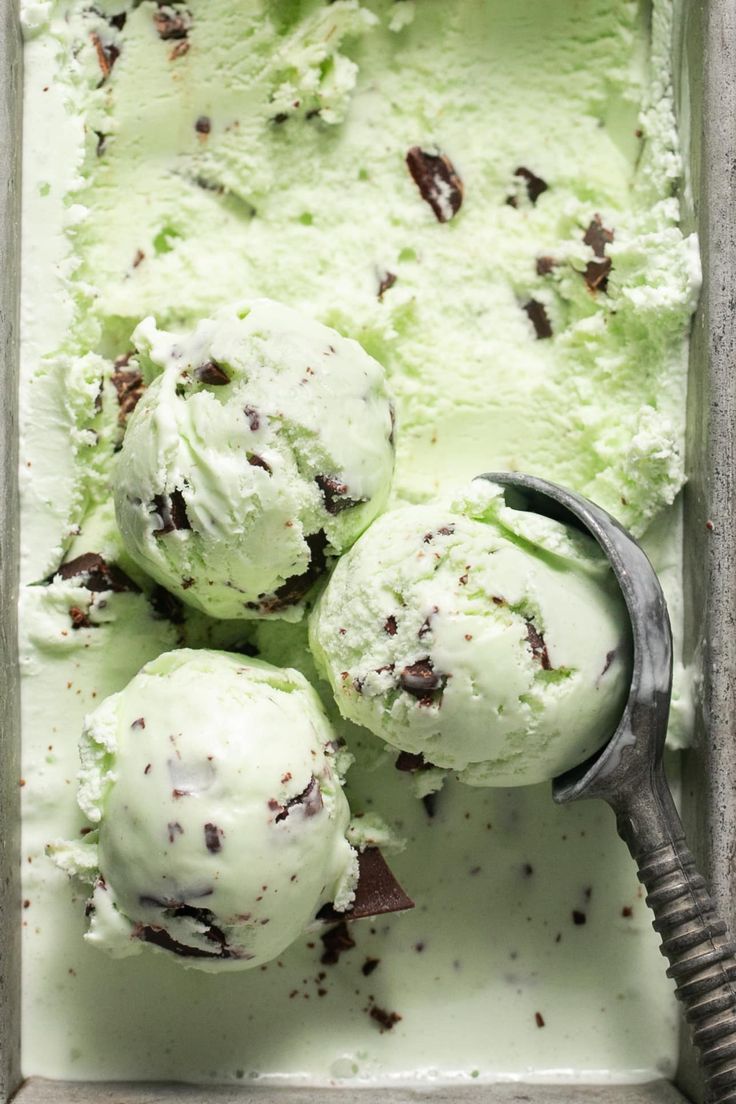 three scoops of ice cream in a metal pan with a spoon on the side