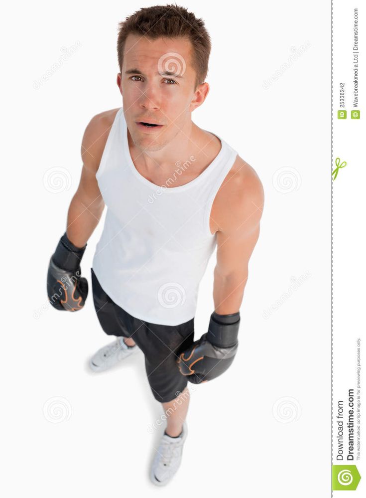 a man in white tank top and black shorts with boxing gloves on his feet, looking up