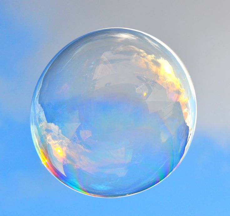 a soap bubble floating in the air on a blue sky with some clouds behind it