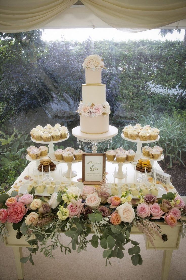 a wedding cake and cupcakes on a table