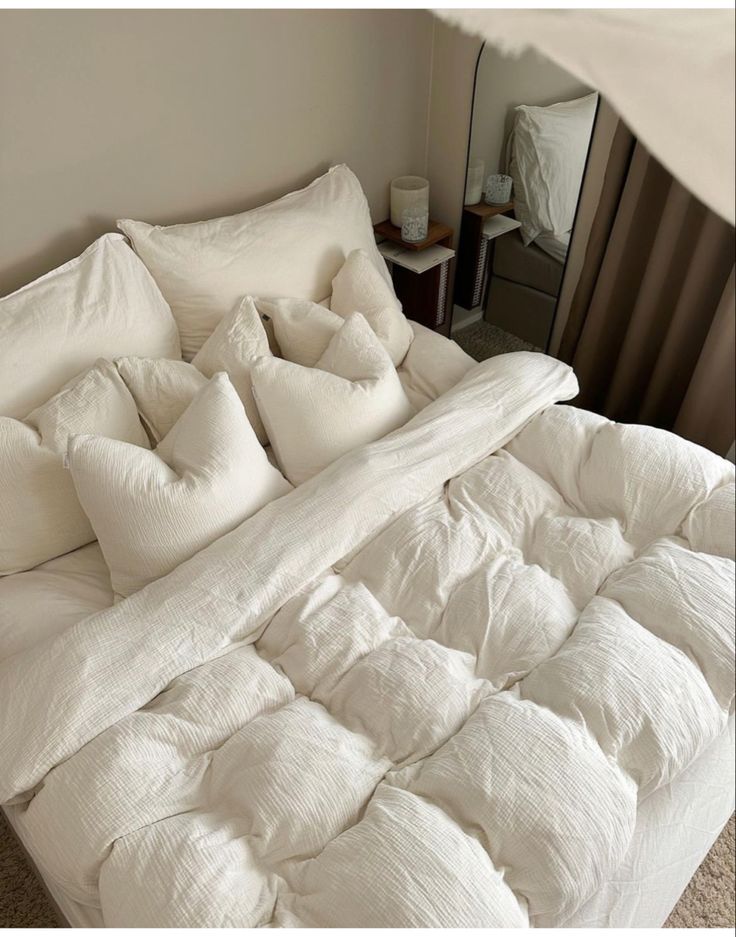 an unmade bed with white sheets and pillows