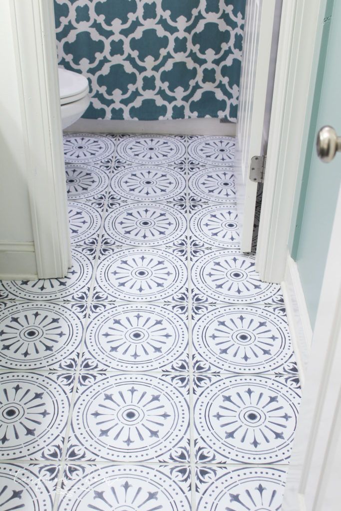 a white toilet sitting next to a blue and white tiled bathroom floor with an open door