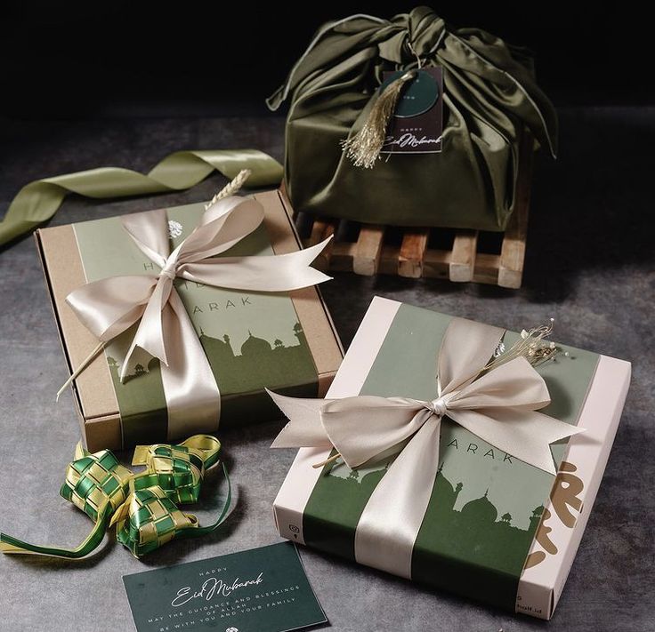 three wrapped gift boxes sitting on top of a table next to ribbons and ribbones