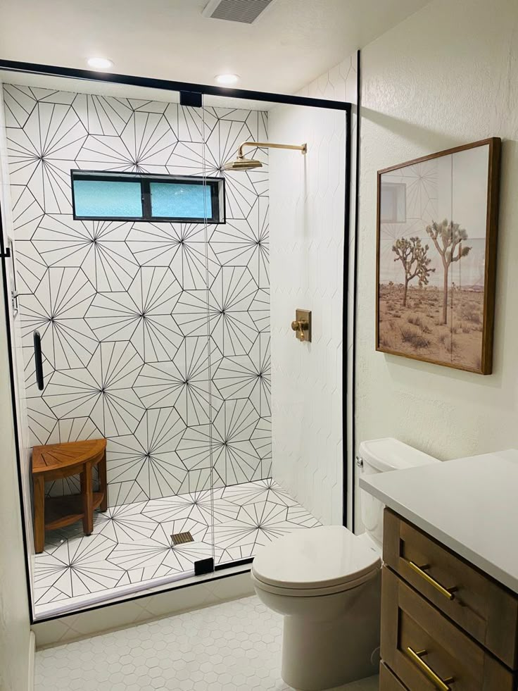 a bathroom with a white toilet sitting next to a walk in shower and wooden cabinets