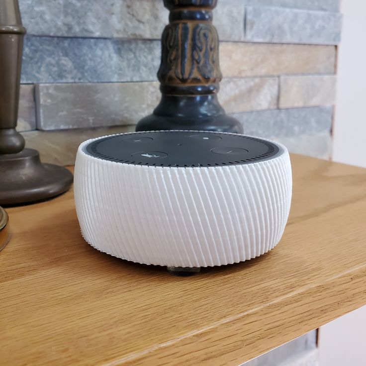 an amazon echo speaker sitting on top of a wooden table next to a lamp and other items