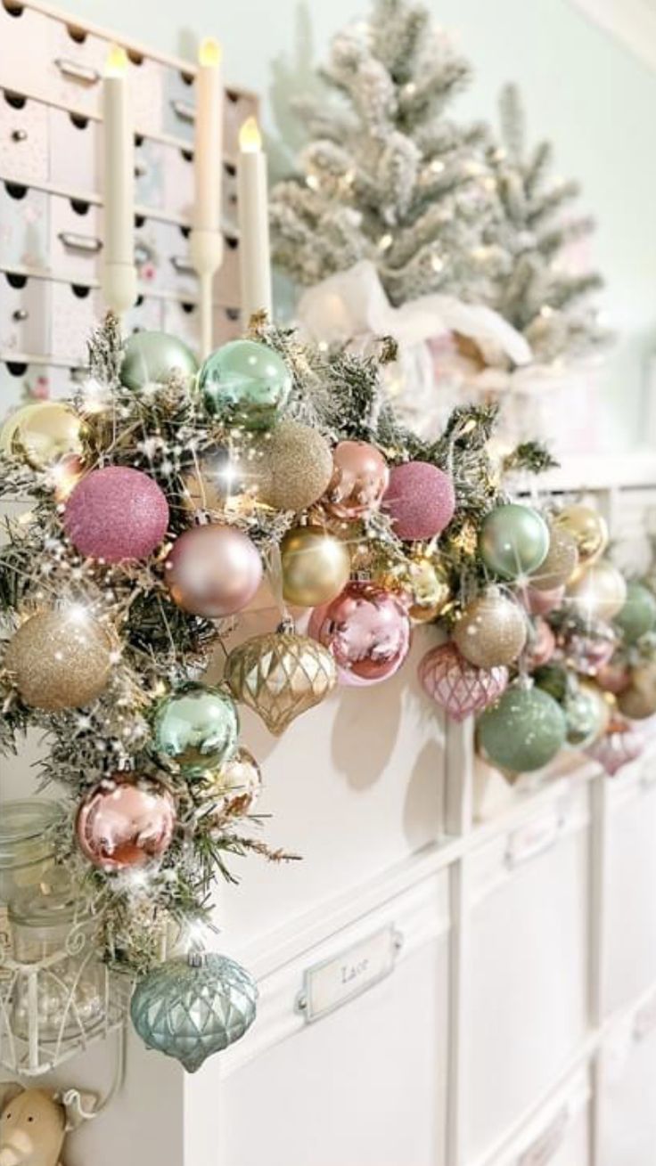 a bunch of ornaments hanging from the side of a white dresser next to a christmas tree