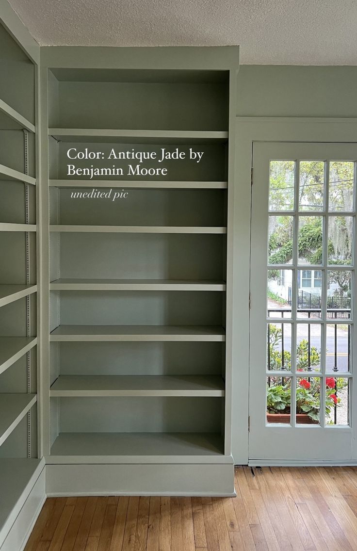 an empty bookcase in the corner of a room with wooden floors and doors open