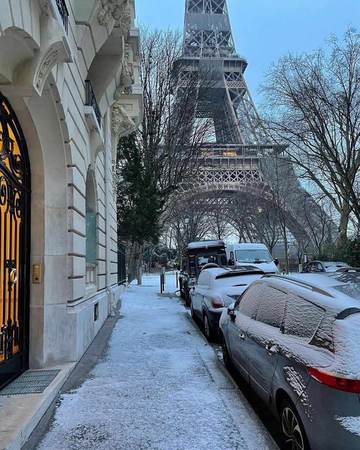 cars are parked in front of the eiffel tower on a snowy winter day