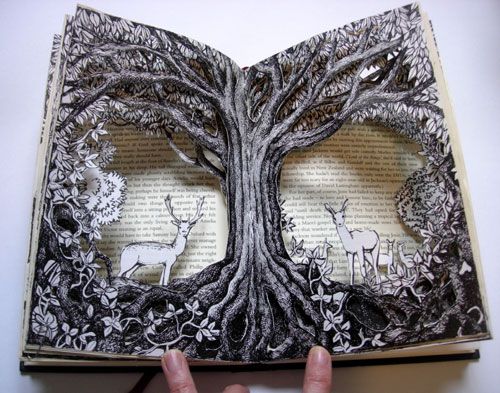 an open book with two deer cut out of it's pages and trees on the inside