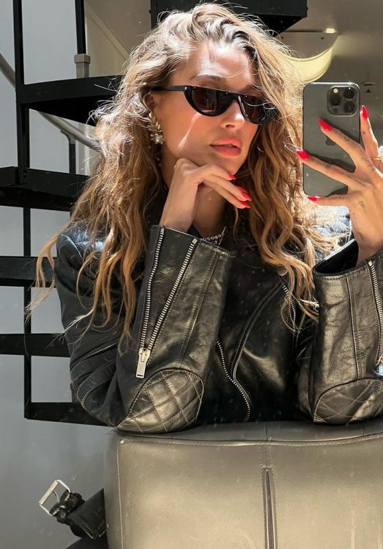 a woman sitting on top of a chair with her hand up to her face and wearing sunglasses