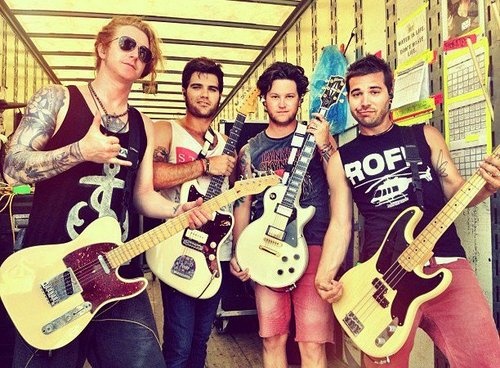 four men are posing with their guitars