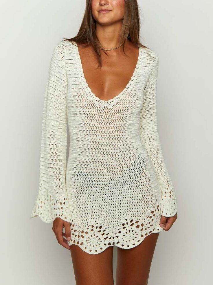 a woman wearing a white crochet sweater and short shorts, posing for the camera