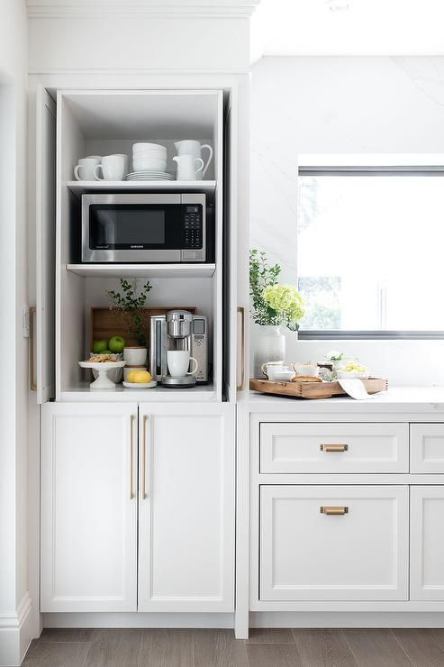 a kitchen with white cupboards and open shelves filled with dishes on top of them