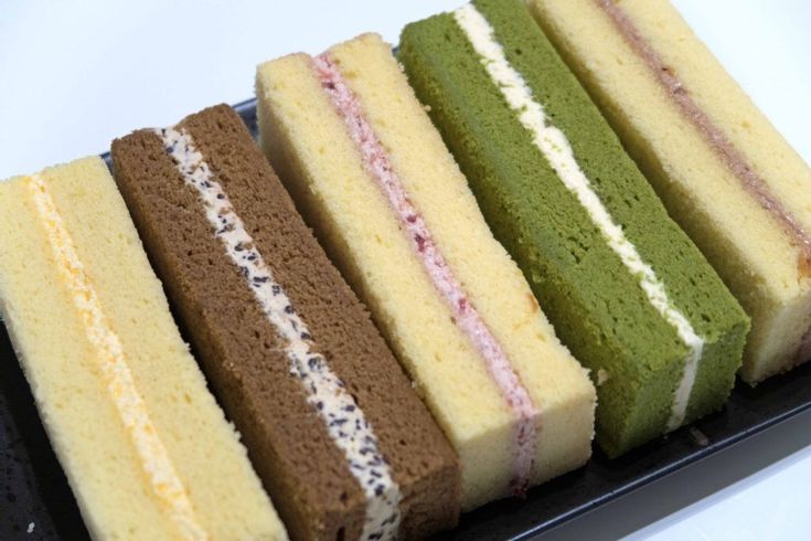 a row of different colored cakes sitting on top of a black tray