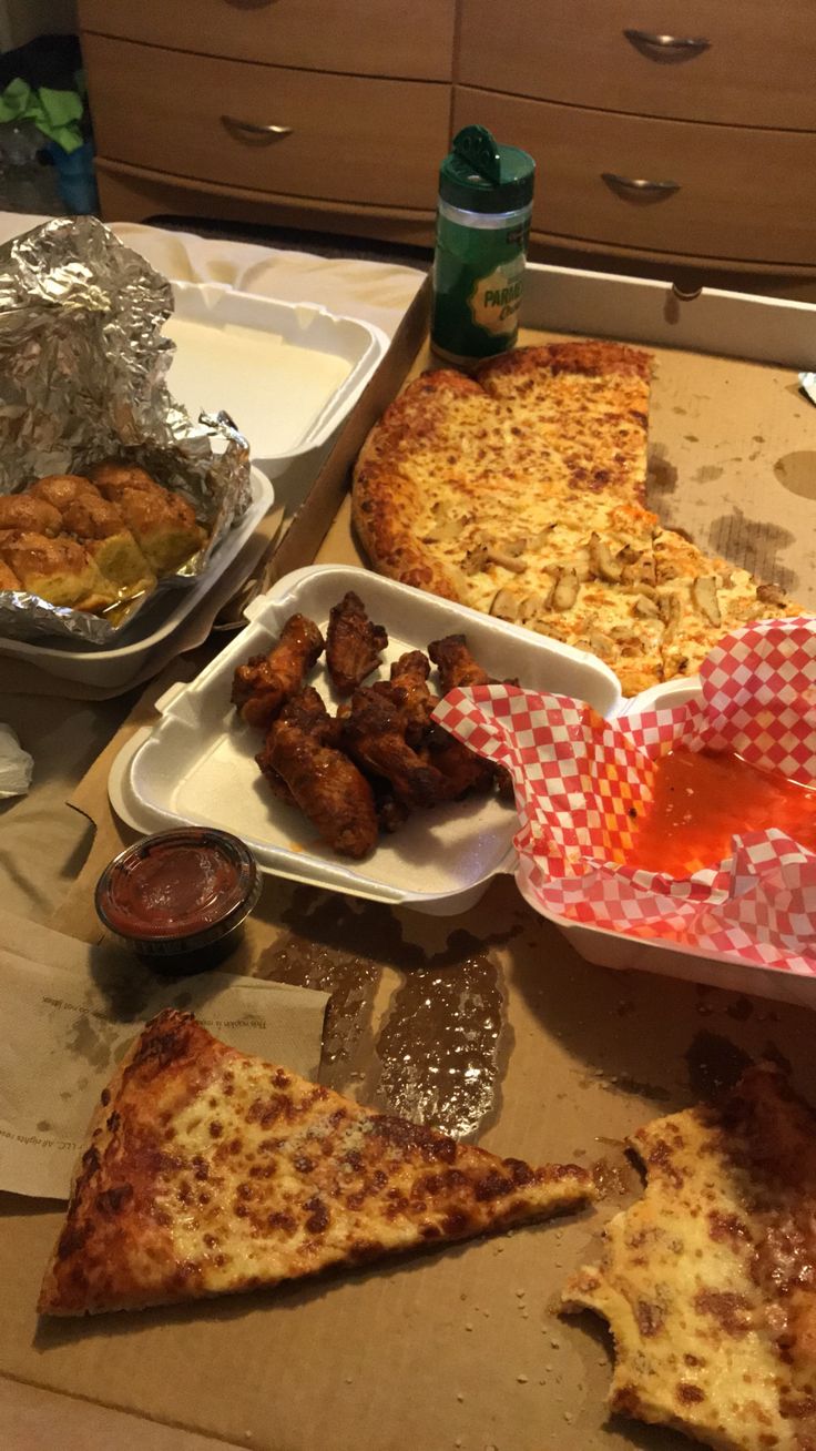 pizza, chicken wings and other foods are on the table