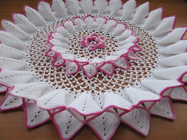 a crocheted doily with pink and white flowers