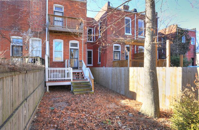 the back yard of an apartment building with fall leaves on the ground and trees in front