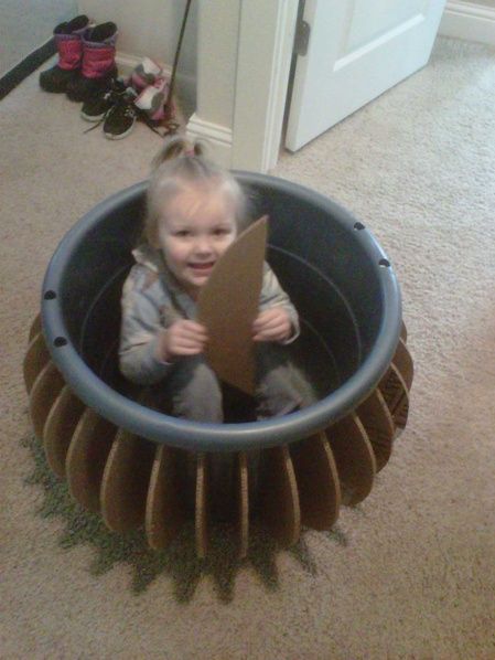 a small child is sitting in a large round object that looks like a rocket ship