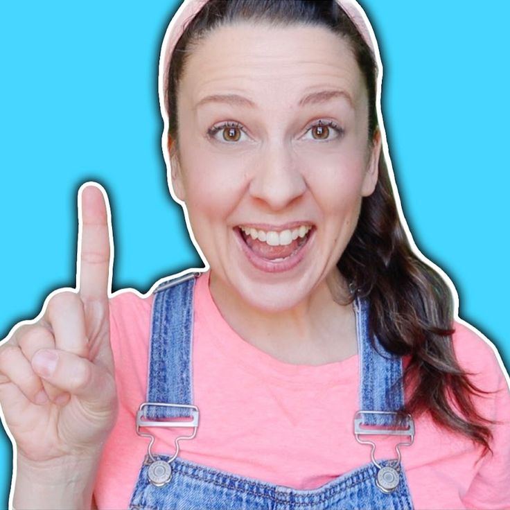 a woman in overalls making the peace sign with her fingers and smiling at the camera