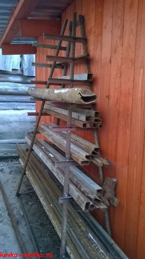 an old ladder leaning up against a wall next to some wooden planks and boards