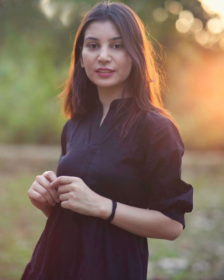 a woman is standing in the grass with her hands on her chest and looking at the camera