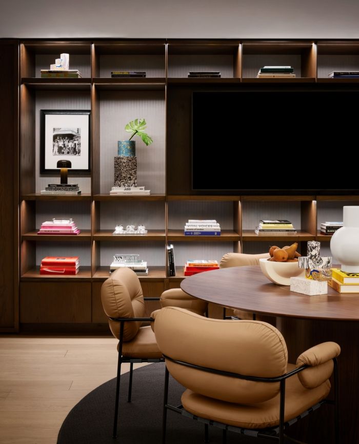 a table with chairs around it in front of a wall mounted tv and bookshelves