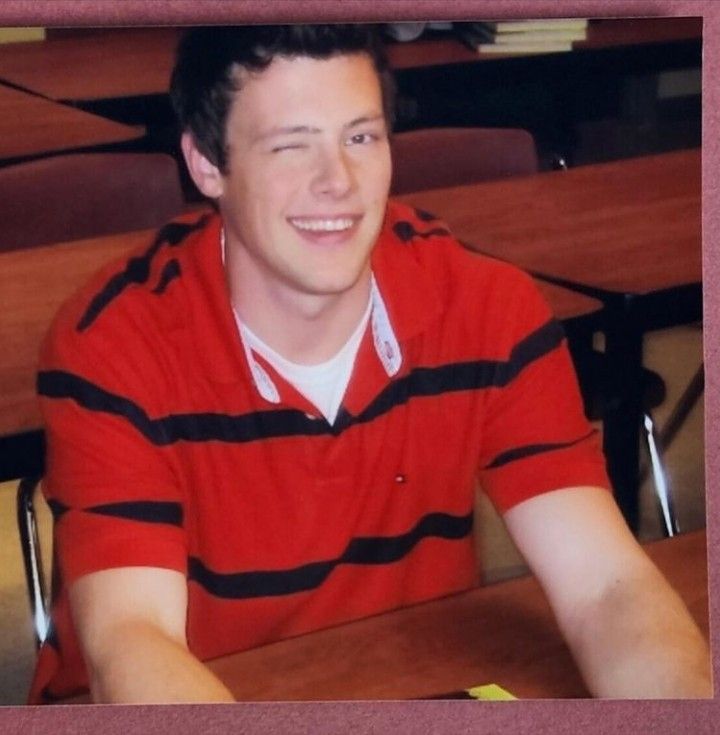 a young man sitting at a table smiling for the camera